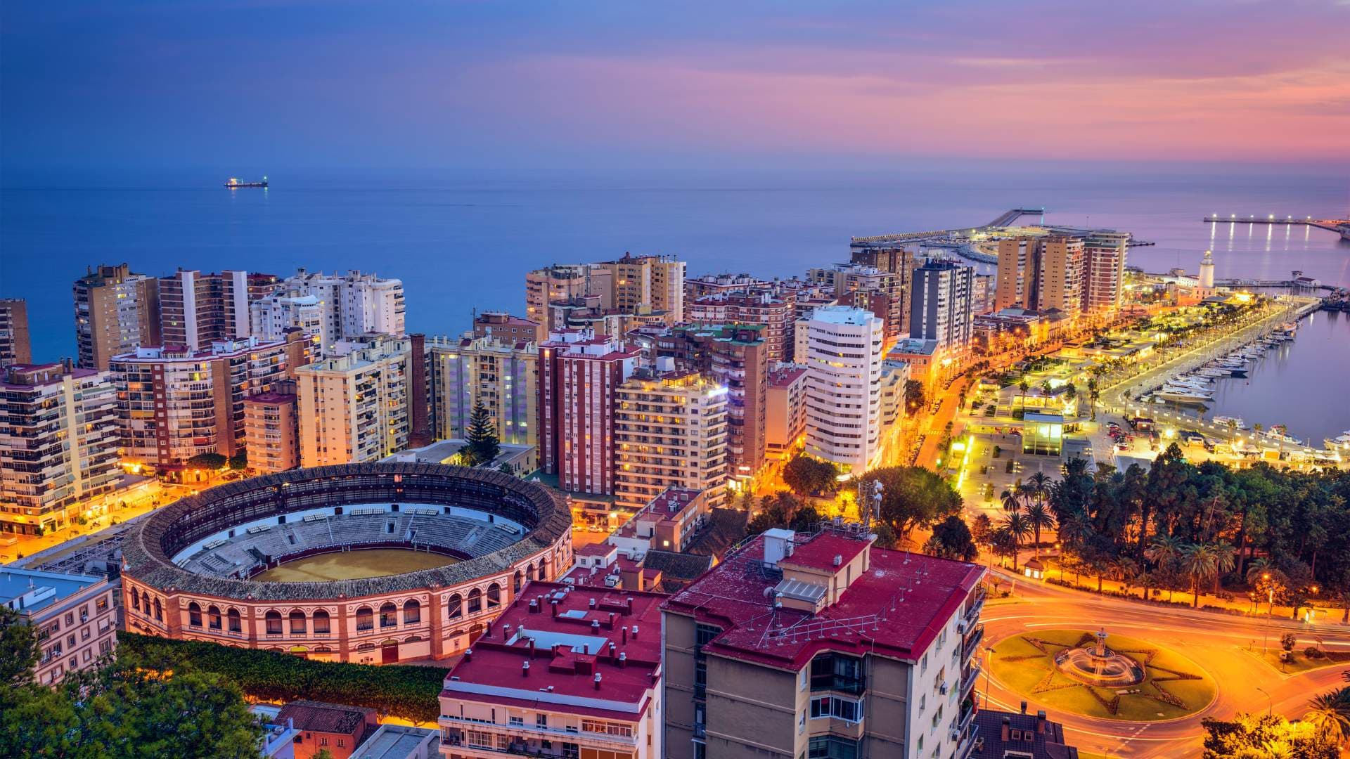 Vista aérea de Málaga al atardecer, con la plaza de toros de La Malagueta y el puerto